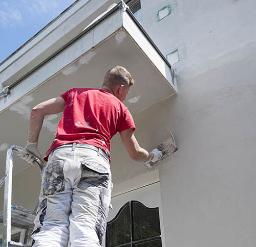 worker on a ladder completing stucco installation on a florida home