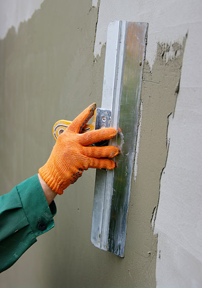 worker using smoothing tool to finish a stucco wall