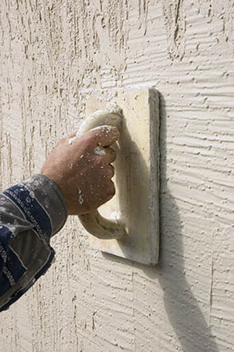worker texturing stucco wall with hand tool