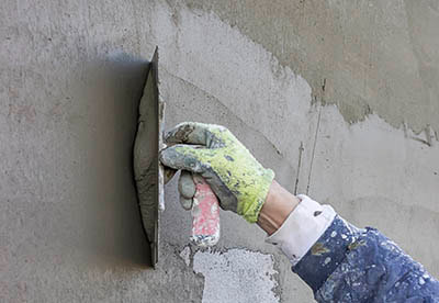 man holding a trowel finishing a stucco wall