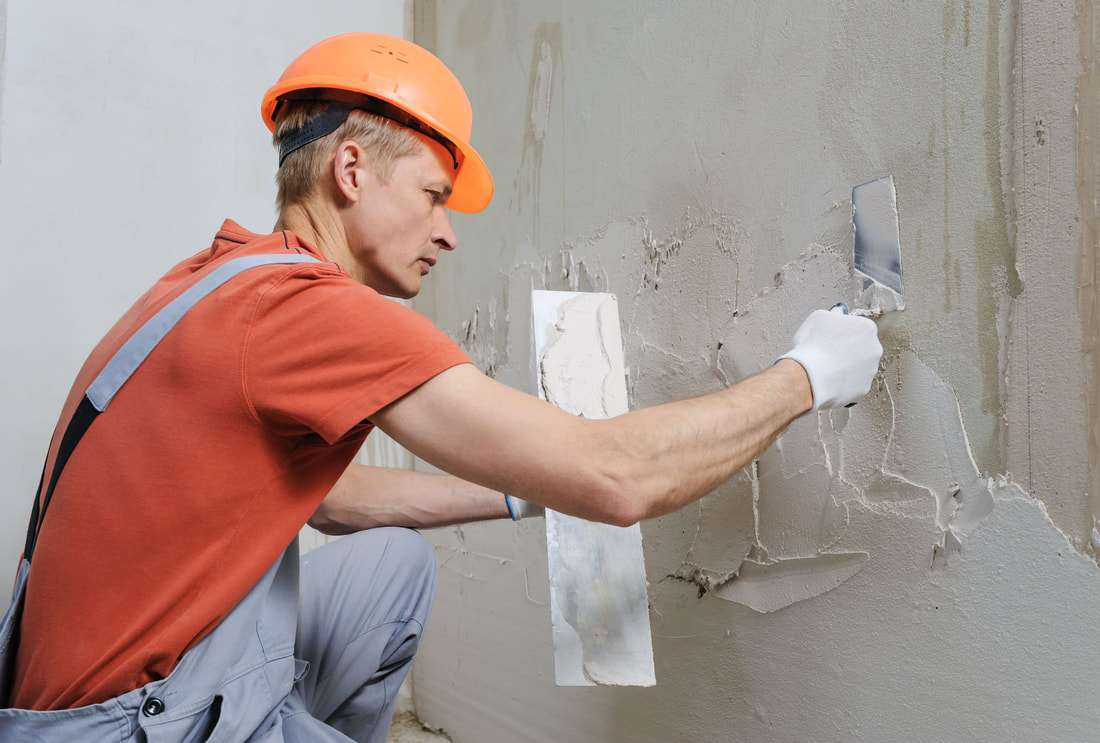 worker troweling and smoothing stucco on concrete wall