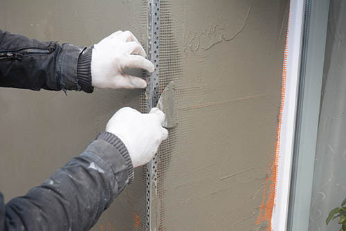 worker applying synthetic stucco over a structural mesh